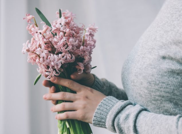 Young woman holding hyacinth flowers bouquet. Toned image By Yulia Grigoryeva via Shutterstock